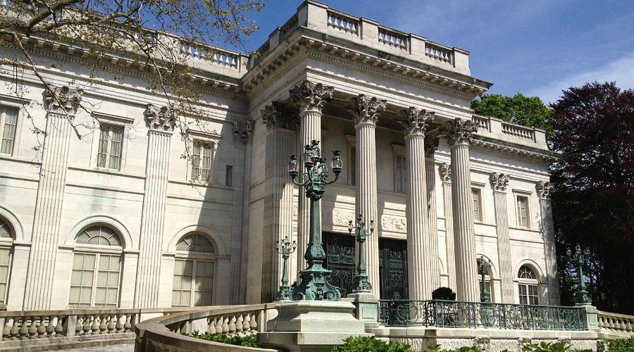 A large white building with columns and a statue in front of it.