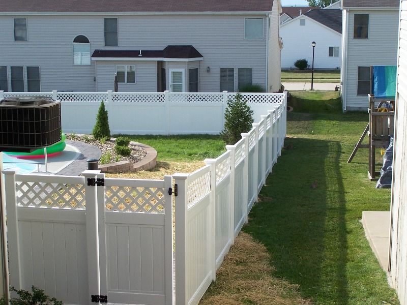 White vinyl fence surrounds a grassy backyard. A gate is visible.
