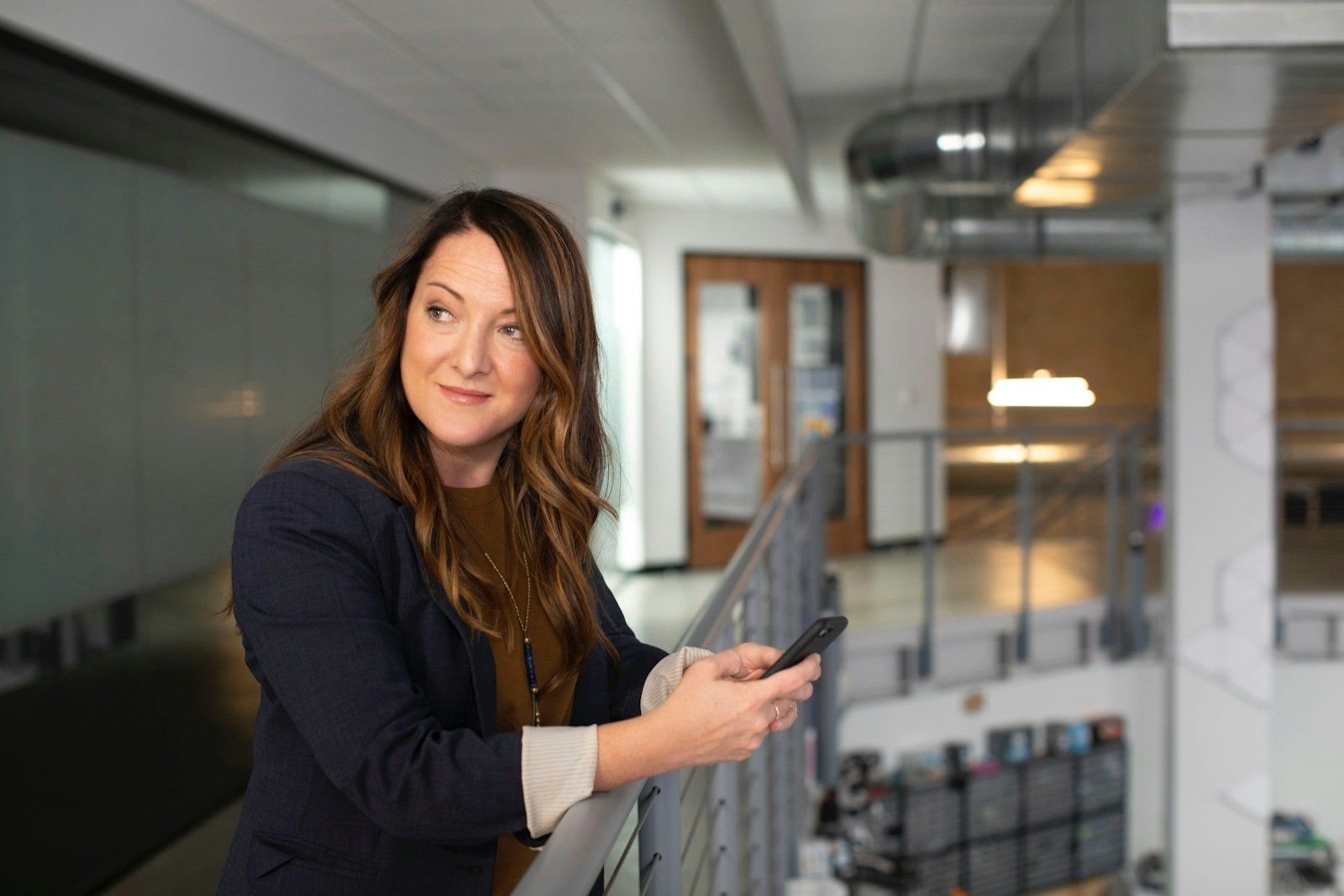 A woman is leaning on a railing while holding a cell phone.