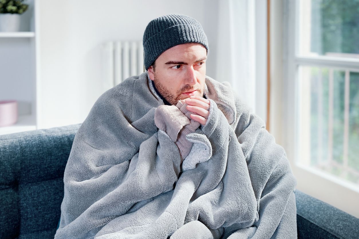 A frustrated homeowner cold in their home while their heater blows cool air.
