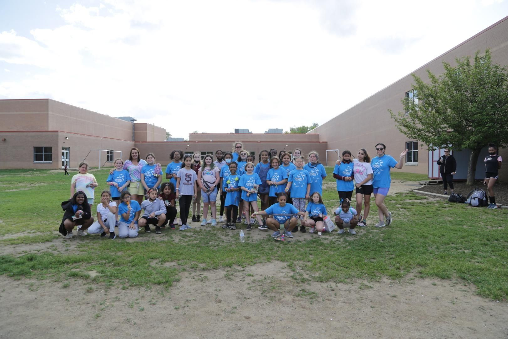 A group of children in blue shirts are posing for a picture