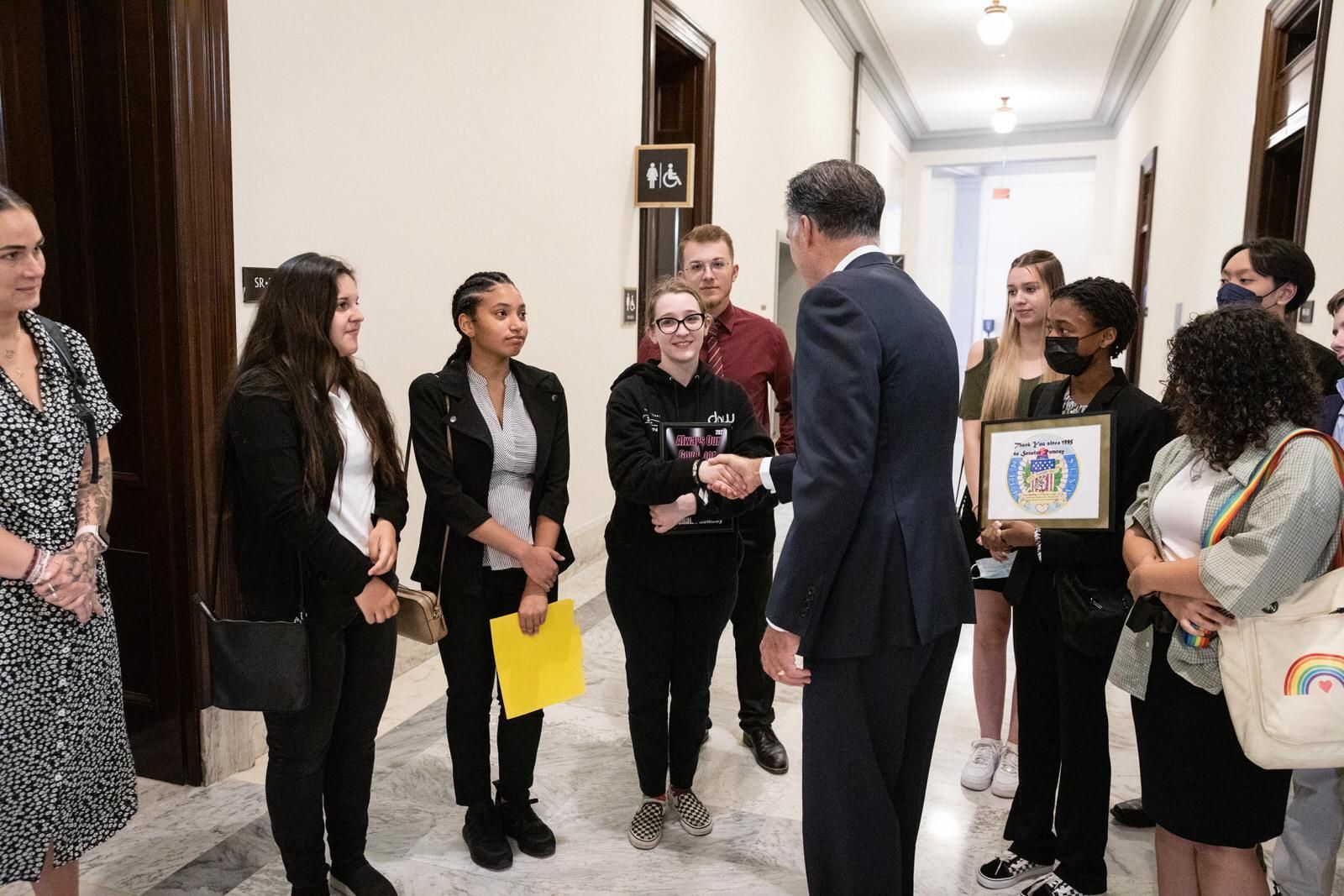 A group of people standing in a hallway with a sign that says 16