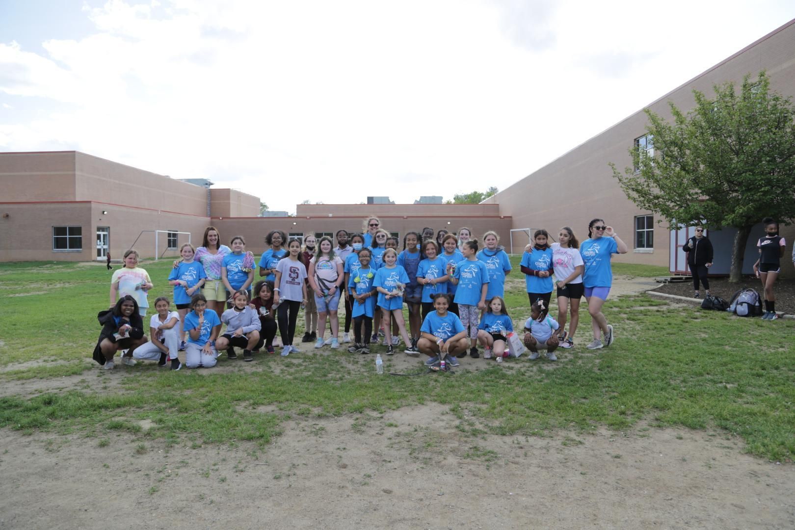 A group of children are posing for a picture in front of a building that says omega