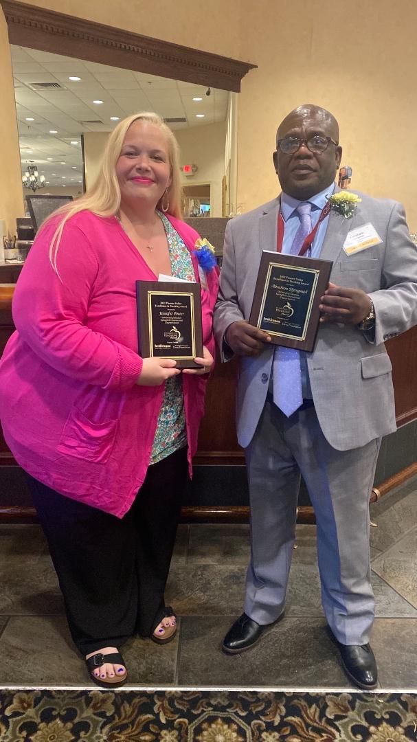 A man and a woman are standing next to each other holding plaques.