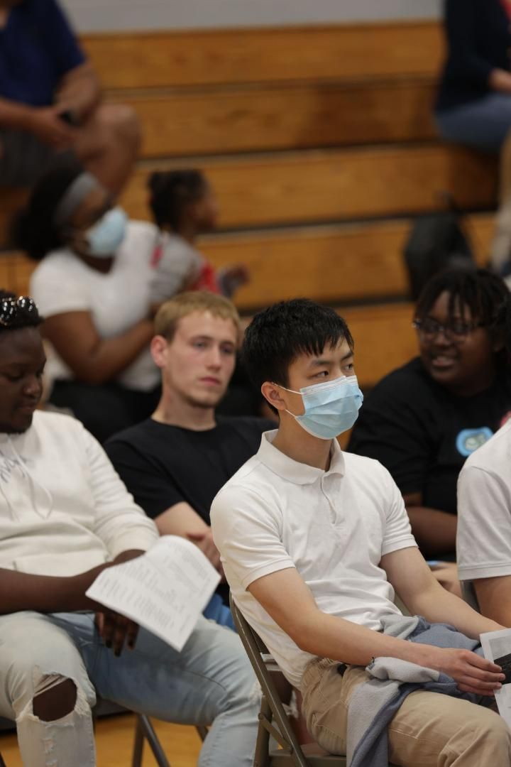 A group of people wearing face masks are sitting in a gym