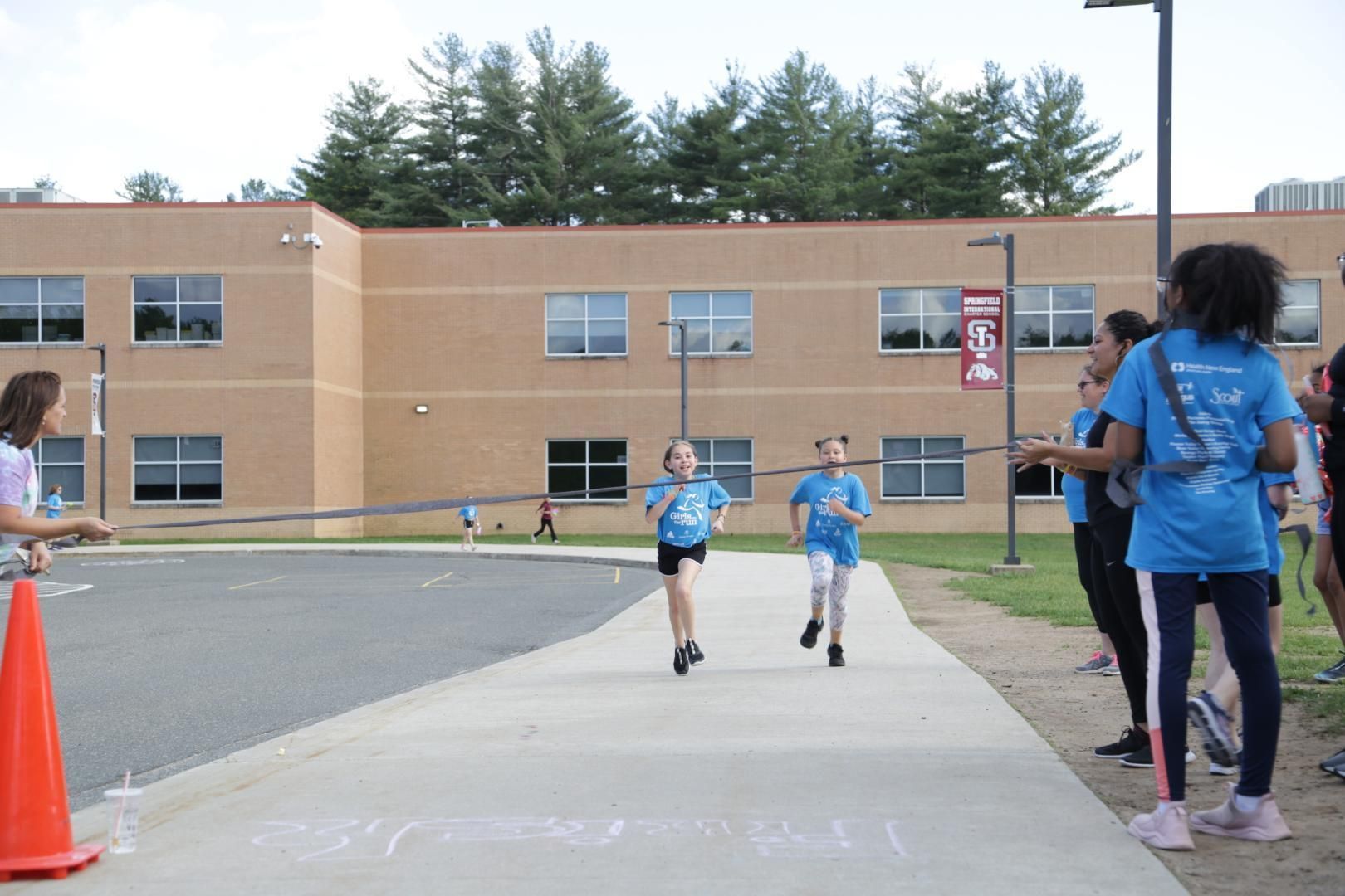 A girl in a blue shirt is running down a sidewalk