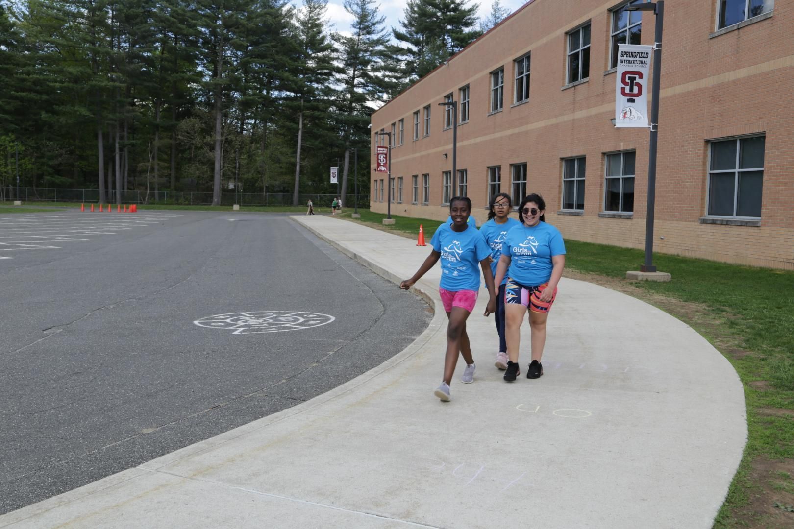 A group of people walking down a sidewalk in front of a building with a sign that says ' army ' on it