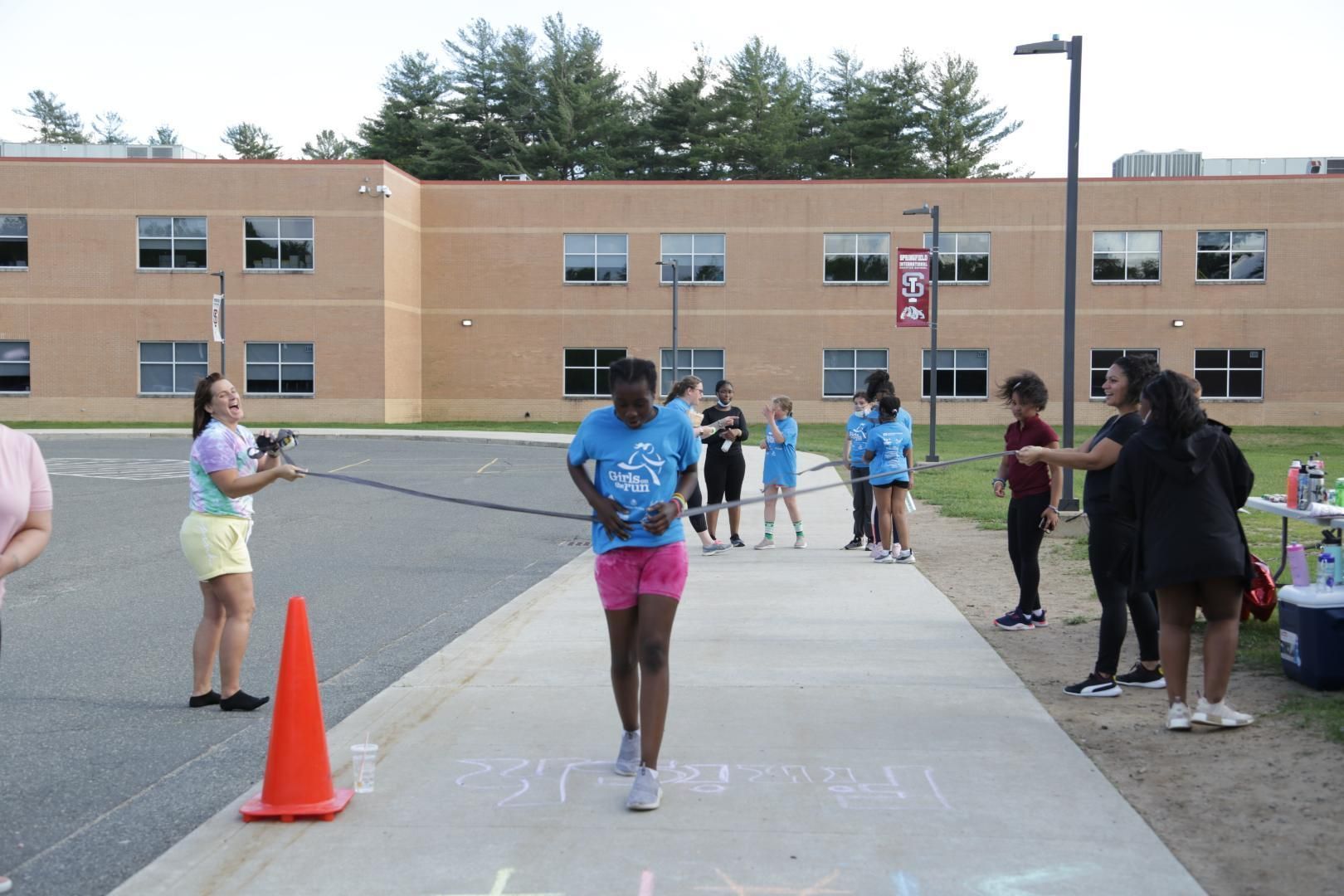 A girl in a blue shirt is running down a sidewalk