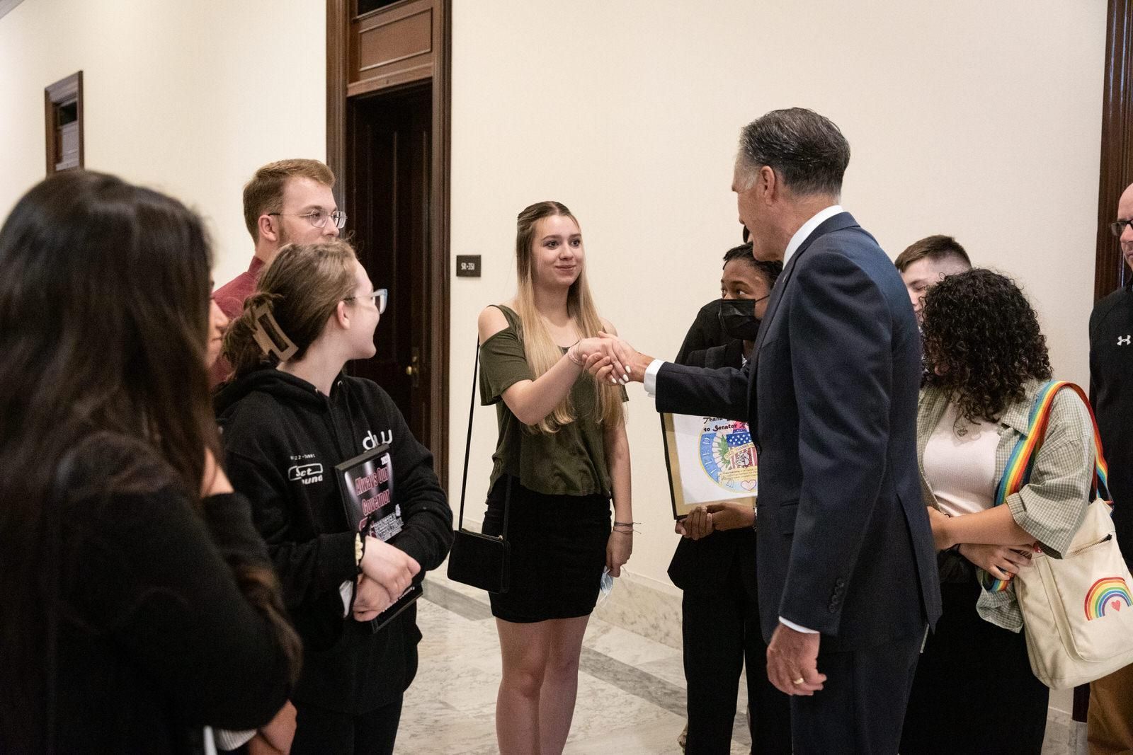 A group of people are shaking hands with a man in a suit