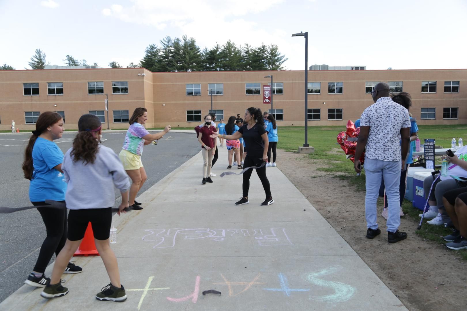 A group of people standing on a sidewalk with the word start written in chalk