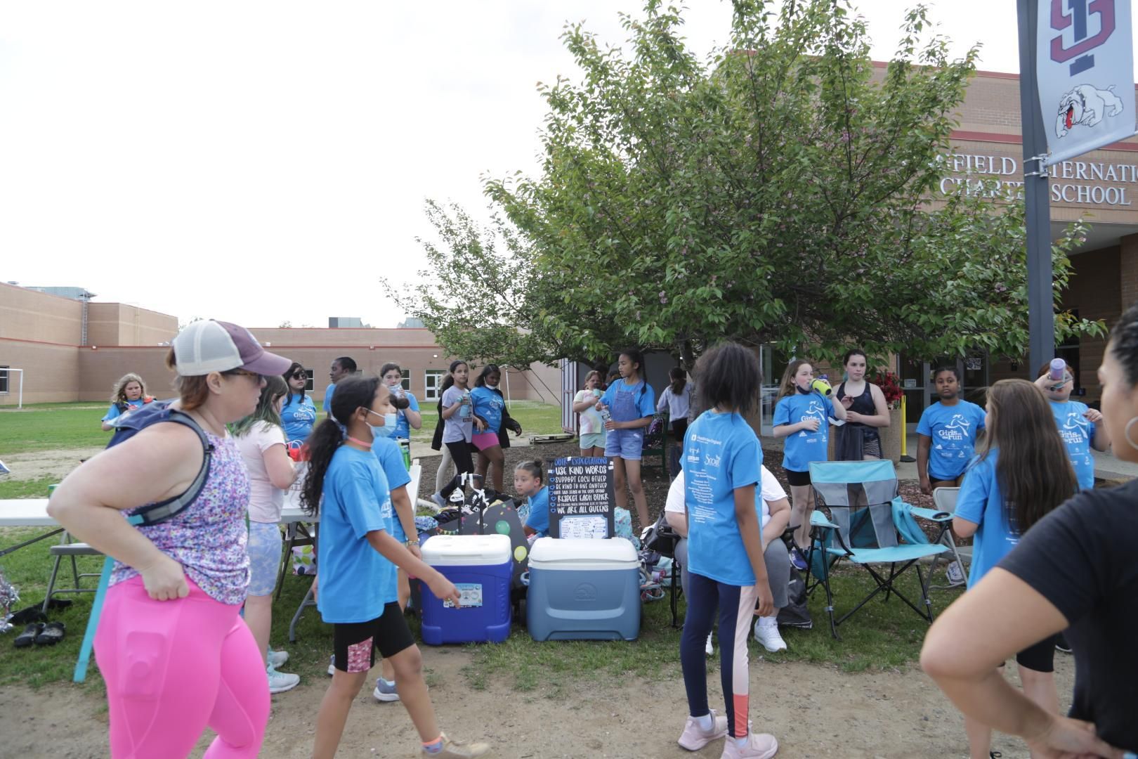 A group of people are gathered in front of a building with the number 53 on it