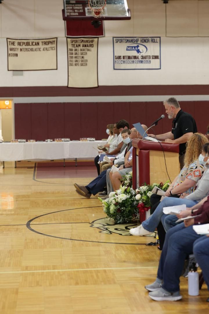 A man is giving a speech to a group of people in a gym