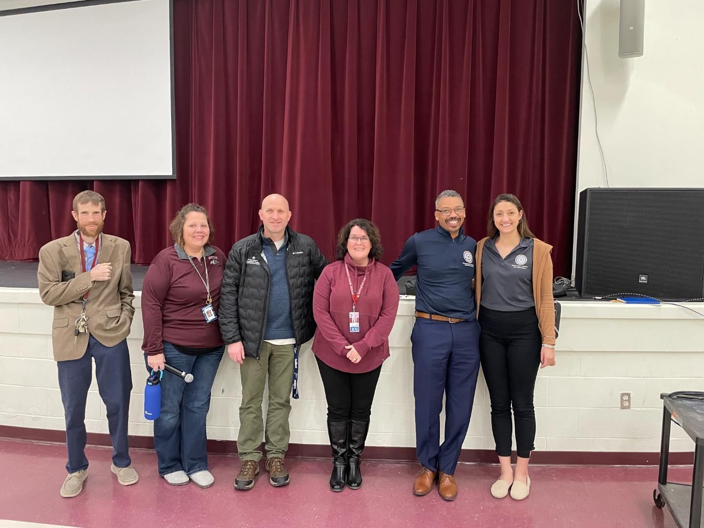 A group of people posing for a picture in front of a red curtain