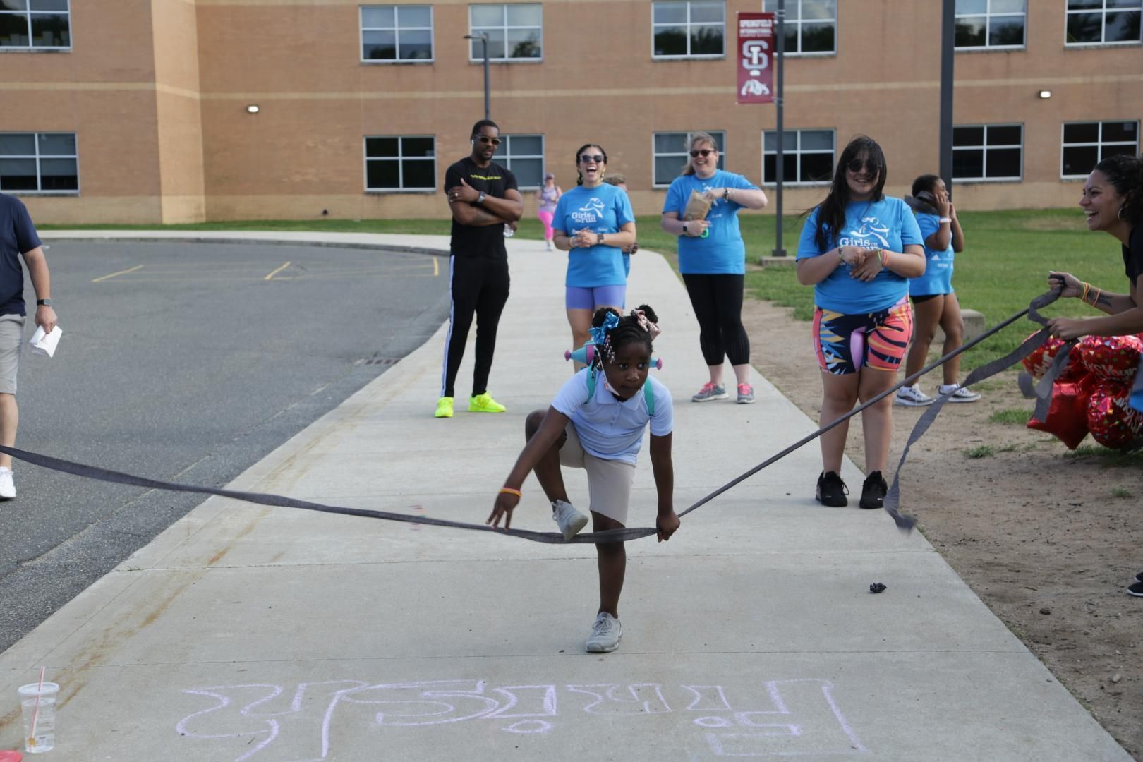 A girl is jumping a rope on a sidewalk in front of a building with the number 36 on it
