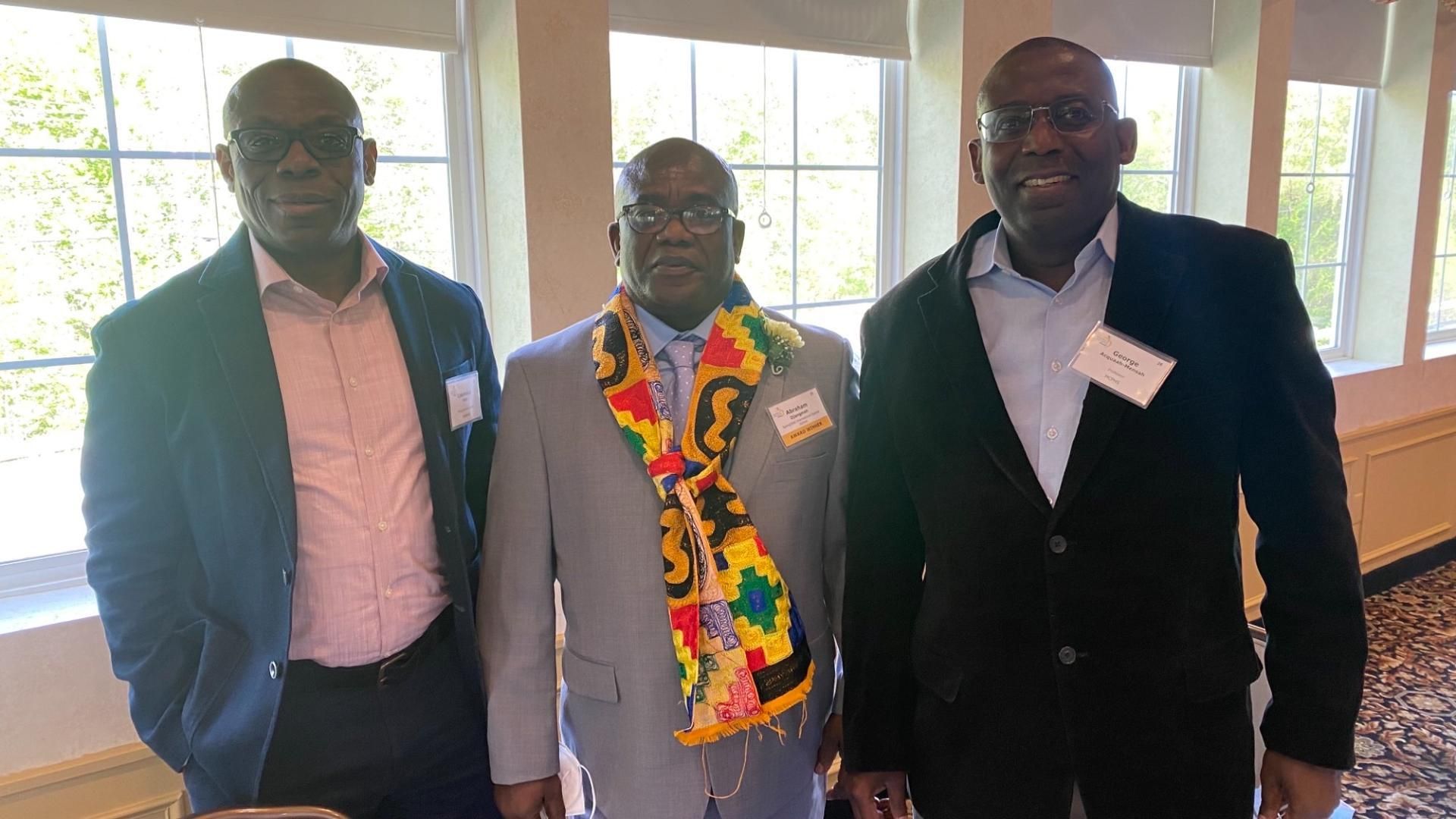 Three men are posing for a picture in front of a window