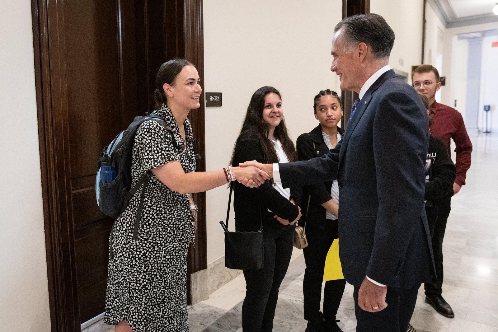 A man in a suit shakes hands with a woman in a dress