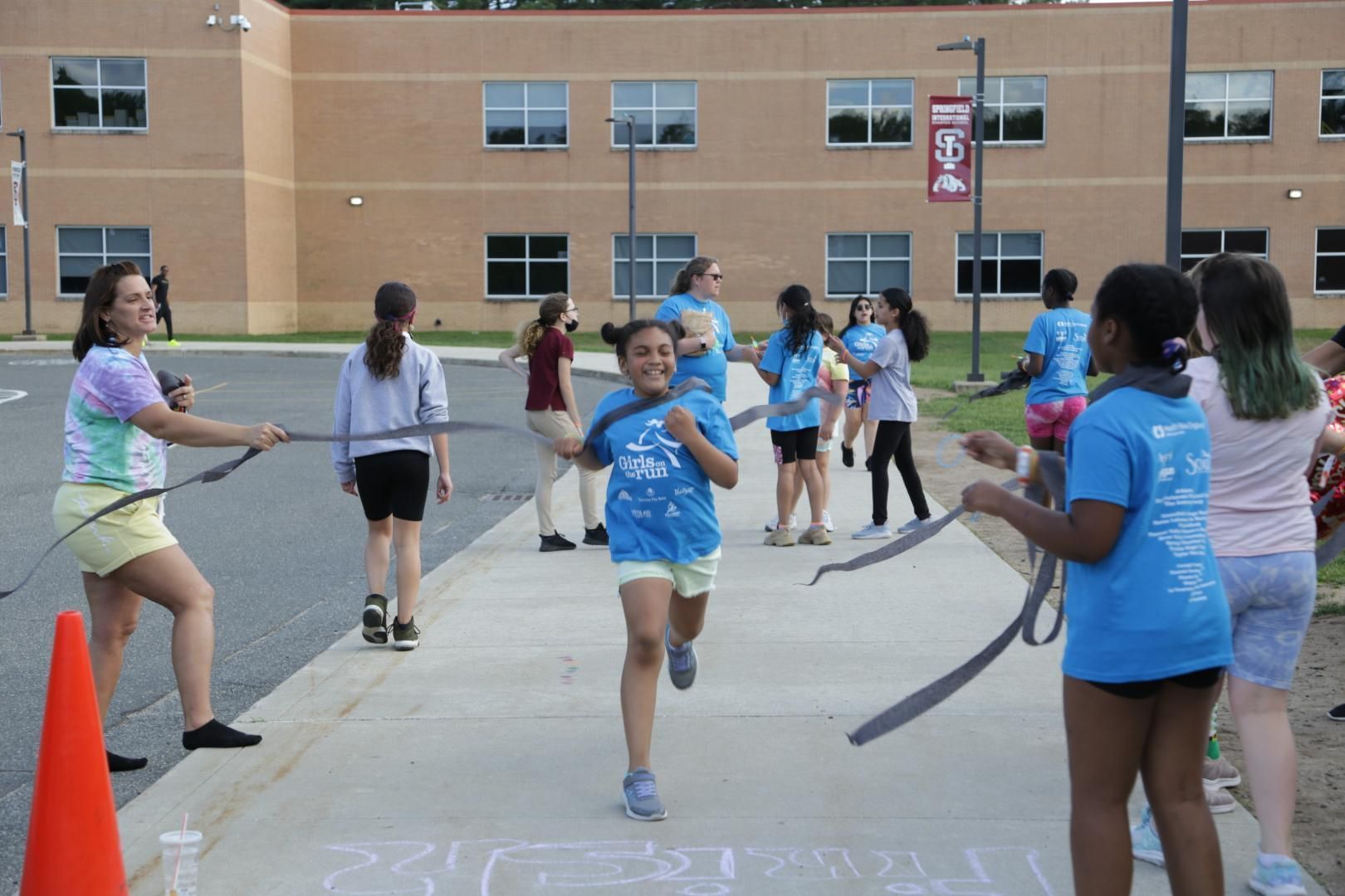 A girl in a blue shirt is jumping a rope