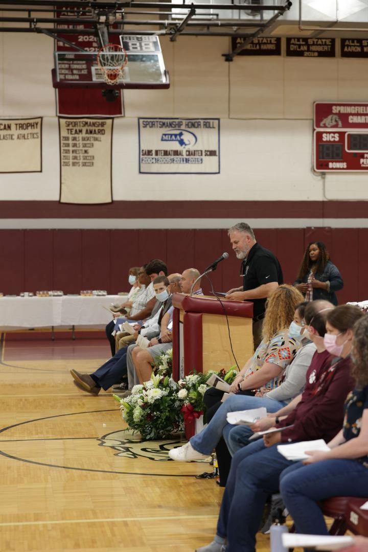 A man is giving a speech to a group of people in a gym