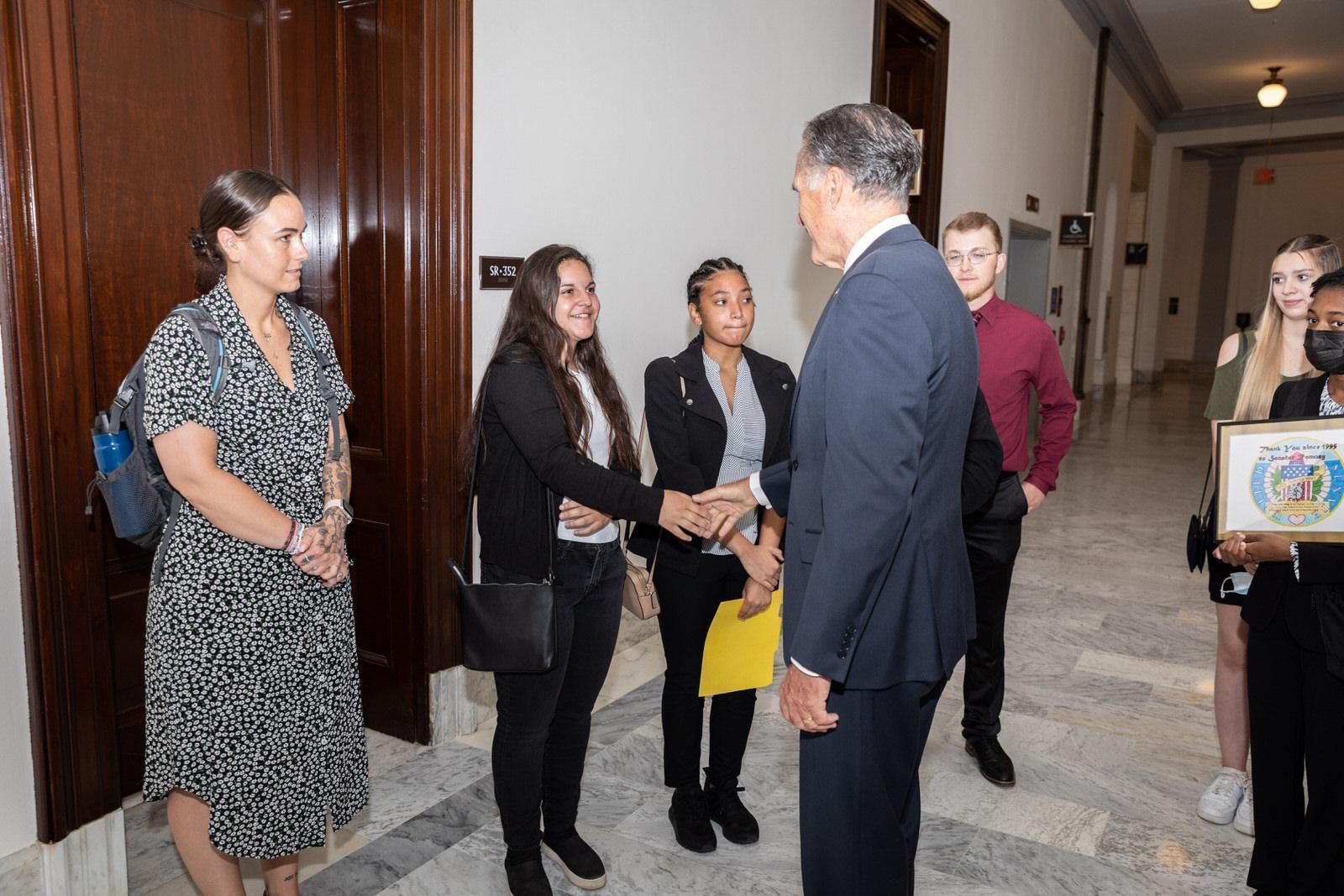 A group of people are shaking hands with a man in a suit