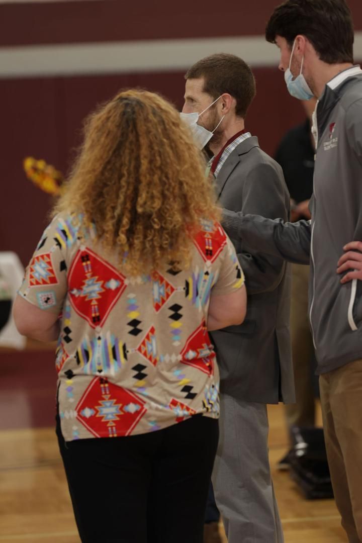 A group of people wearing face masks are standing on a wooden floor
