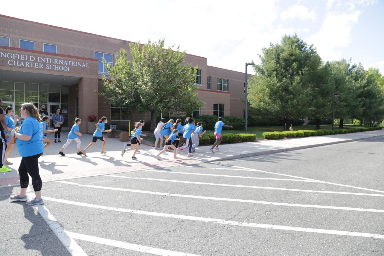 A group of children are crossing the street in front of a school