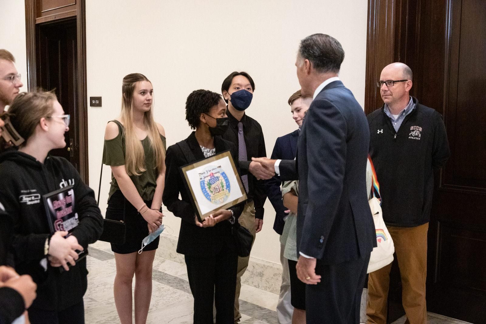 A group of people are standing around a man in a suit
