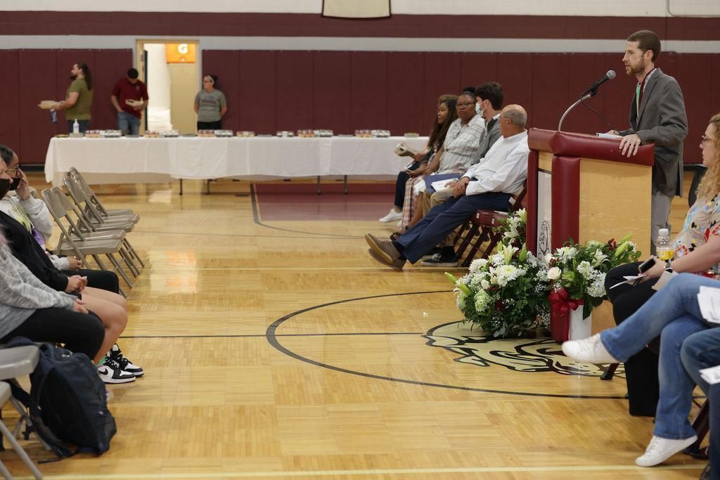A man stands at a podium giving a speech to a group of people