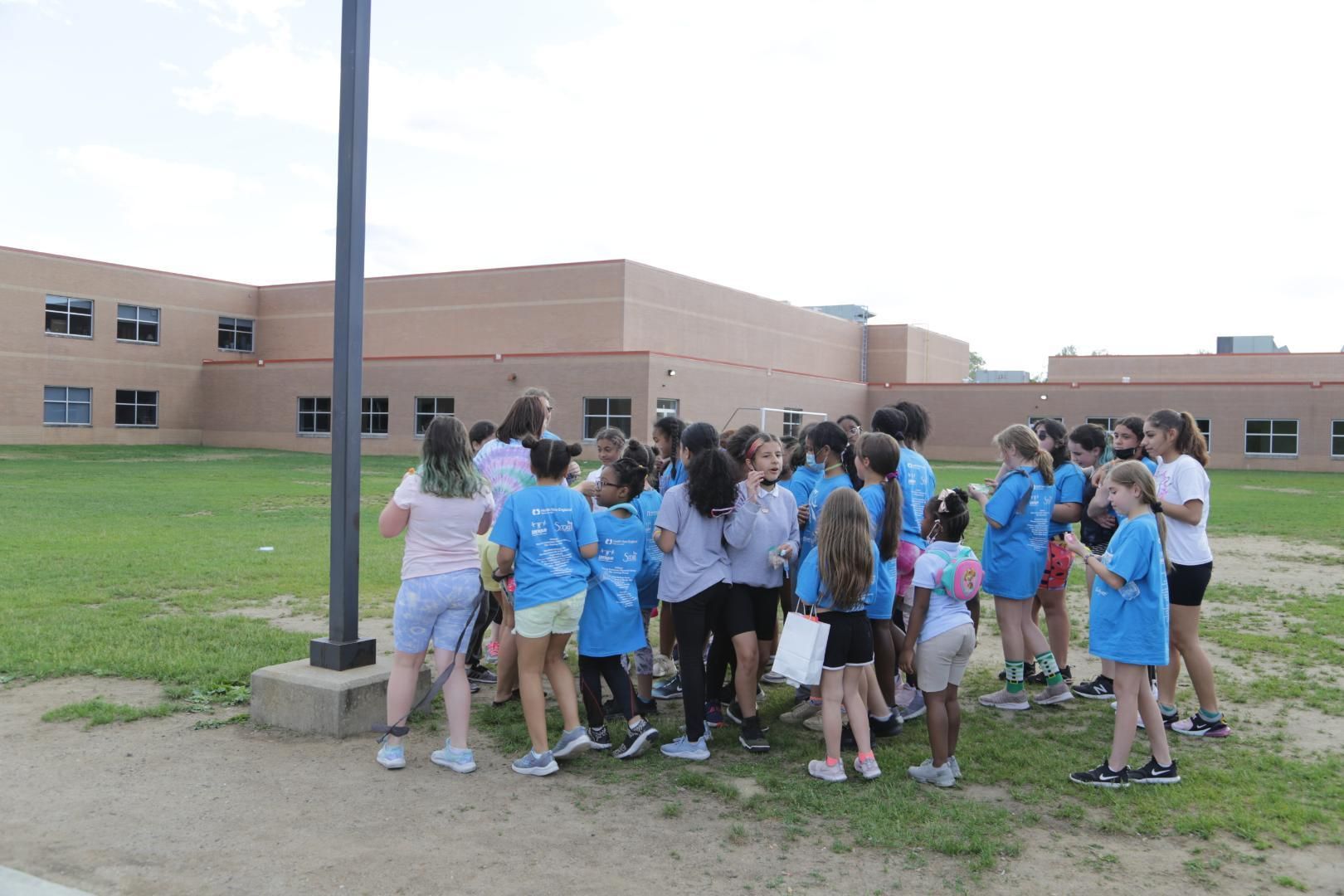 A group of children in blue shirts are standing in a field