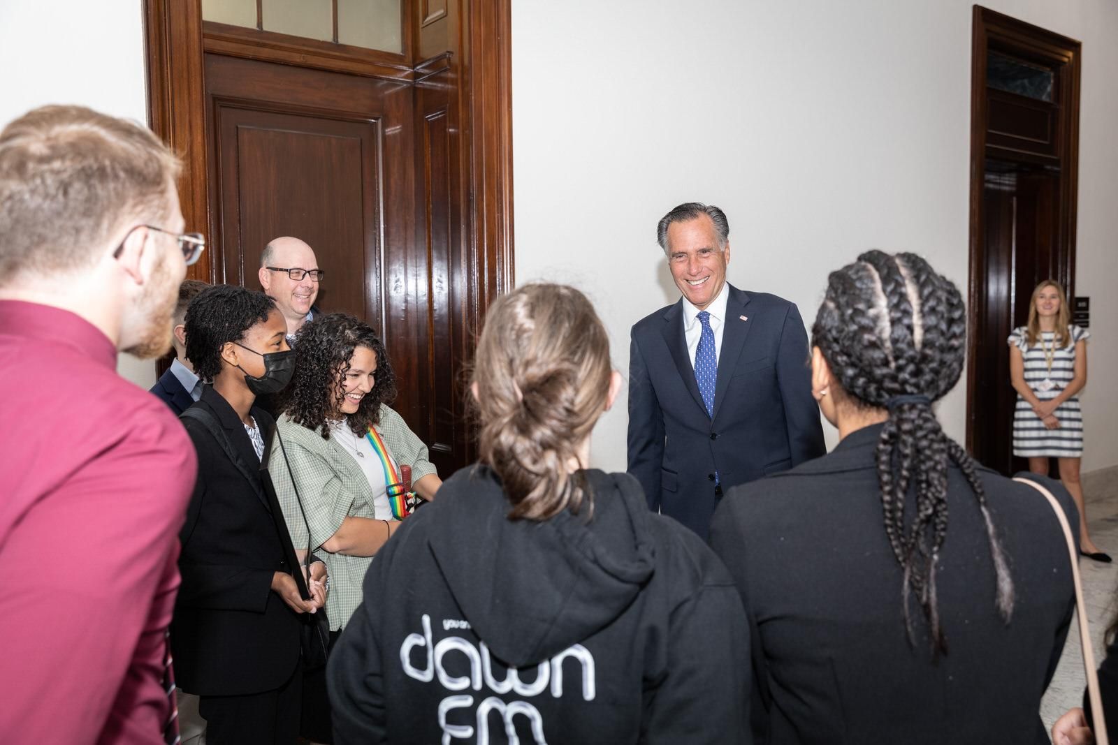 A group of people standing around a man wearing a dawn fm hoodie