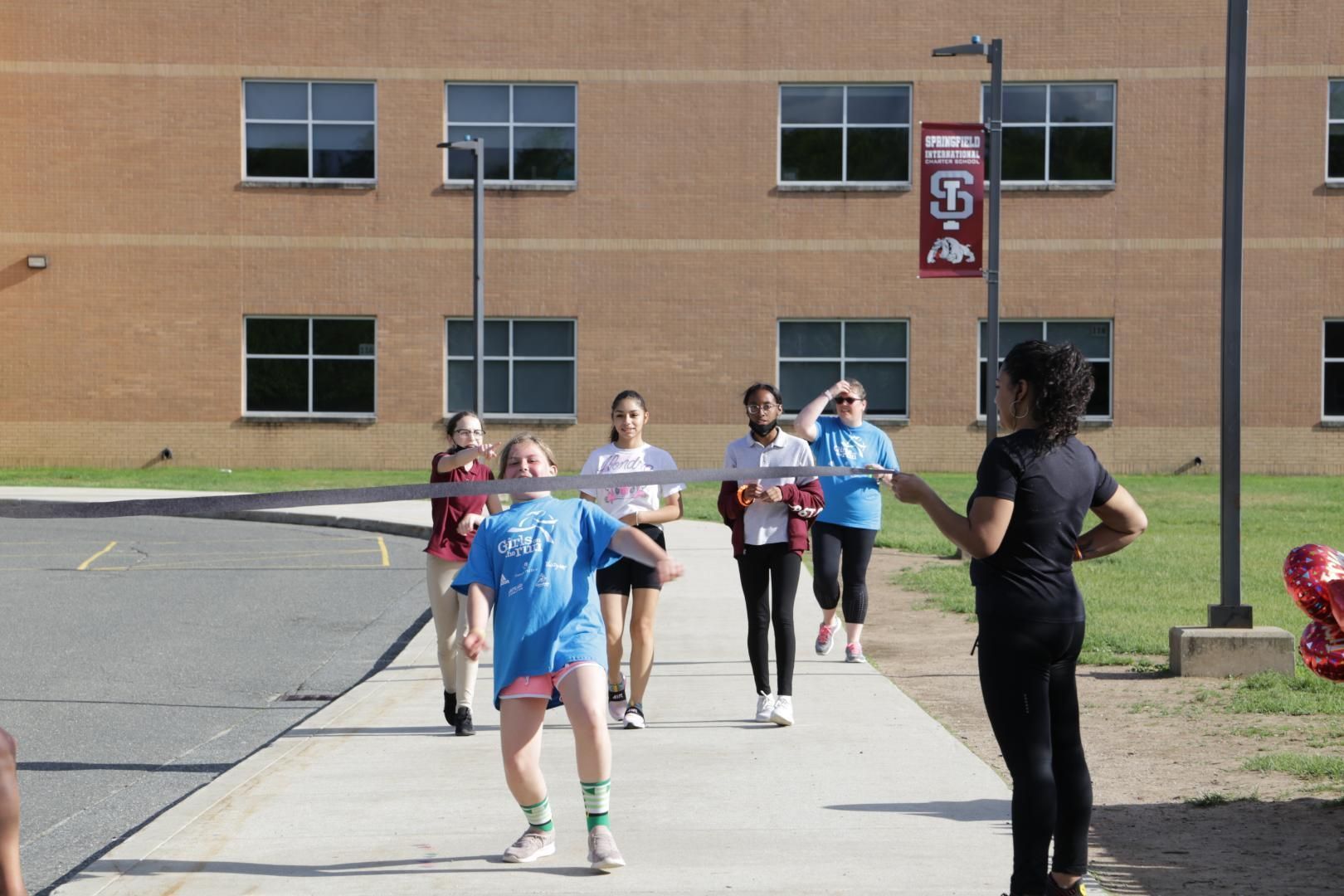 A group of people are walking down a sidewalk in front of a building with a sign that says ' 88 ' on it