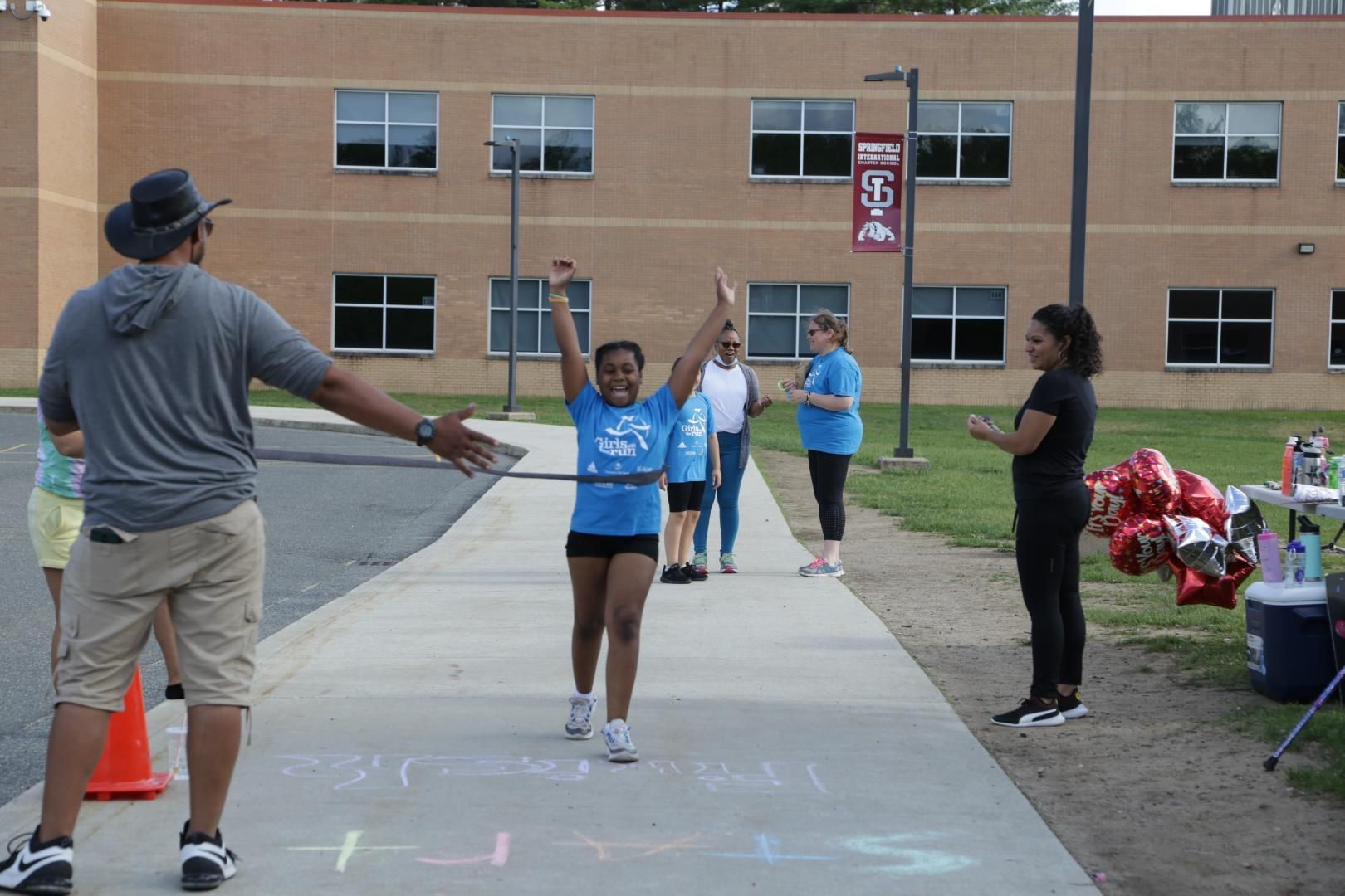 A girl in a blue shirt is running down a sidewalk