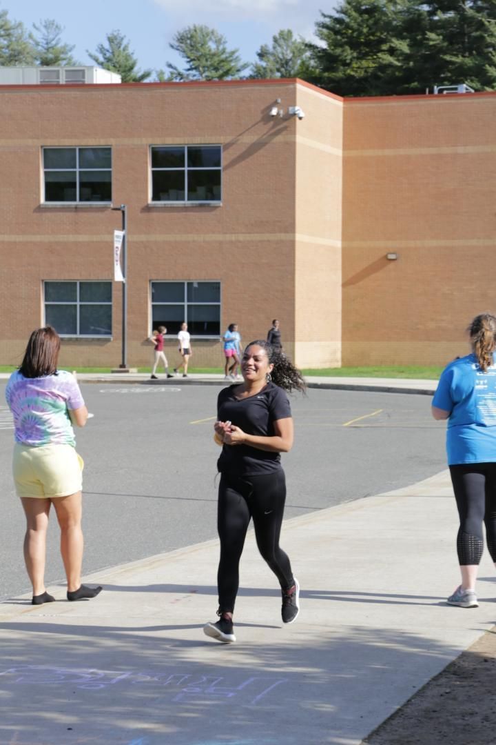 A woman in a black shirt is running in front of a building