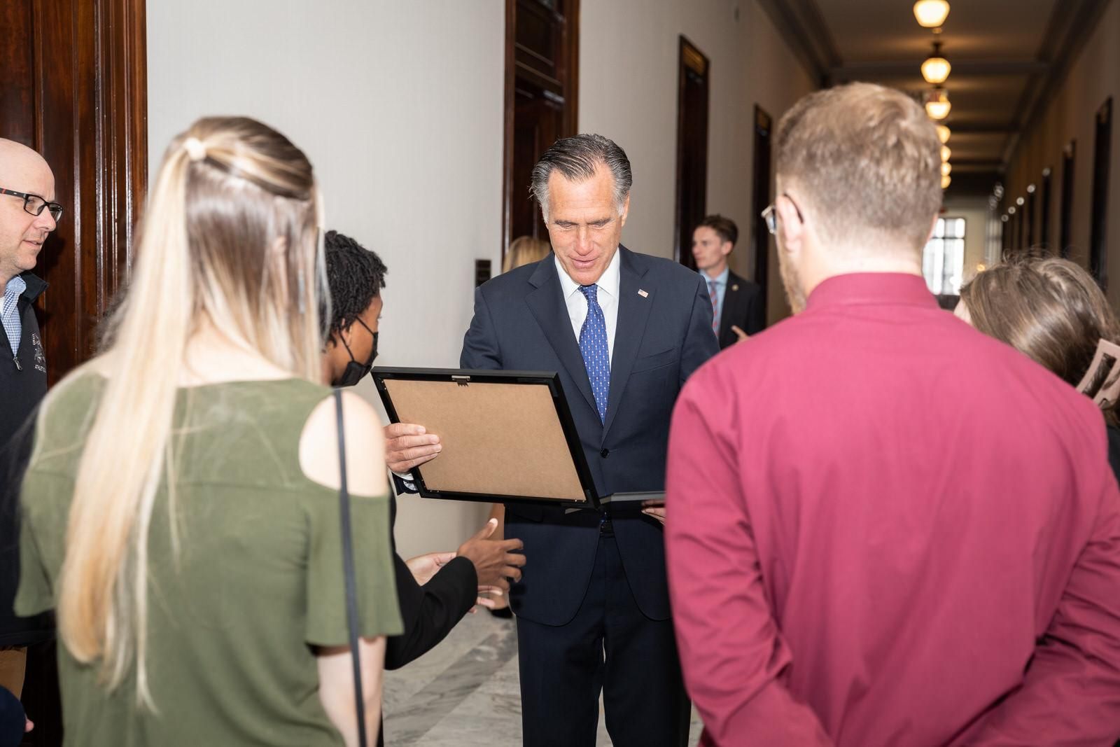 A man in a suit and tie is talking to a group of people