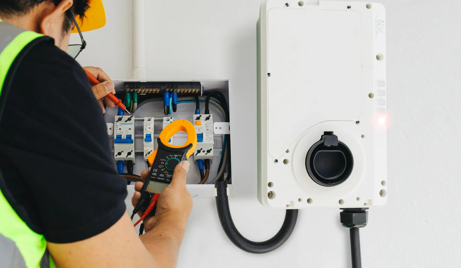 Electrician tests wiring in a panel for a home EV charging station.