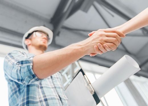 A man in a hard hat is shaking hands with a woman.