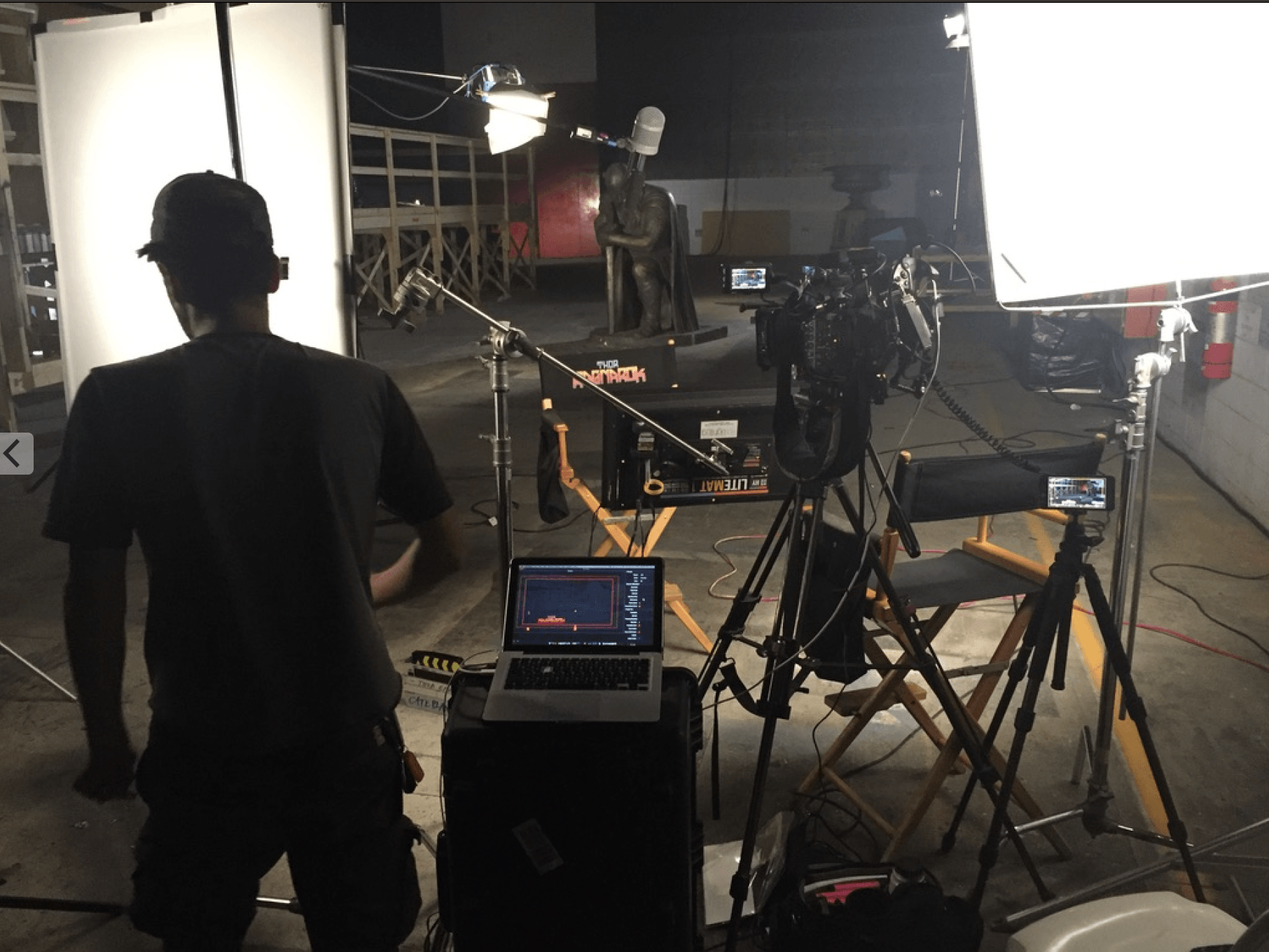 A man is standing in front of a laptop in a dark room.