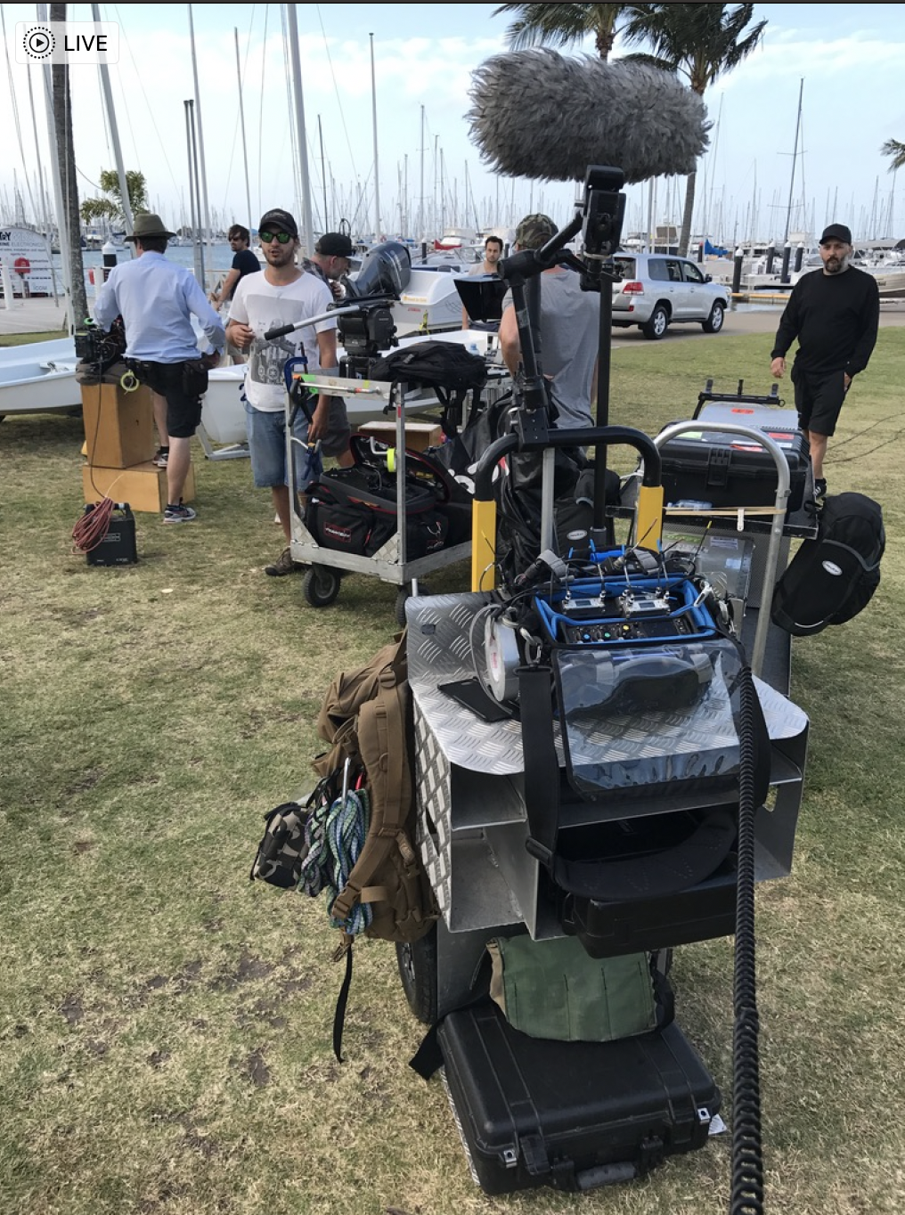 A group of people are standing around a cart with a microphone on top of it.