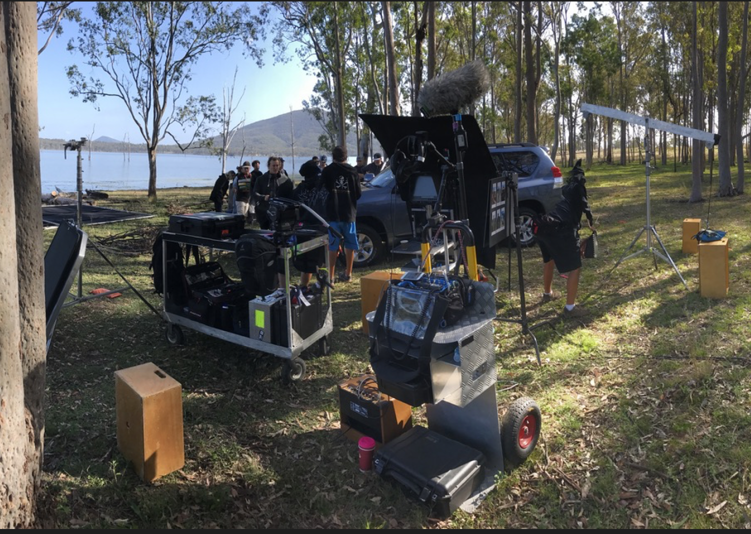 A group of people are standing in a field near a lake.