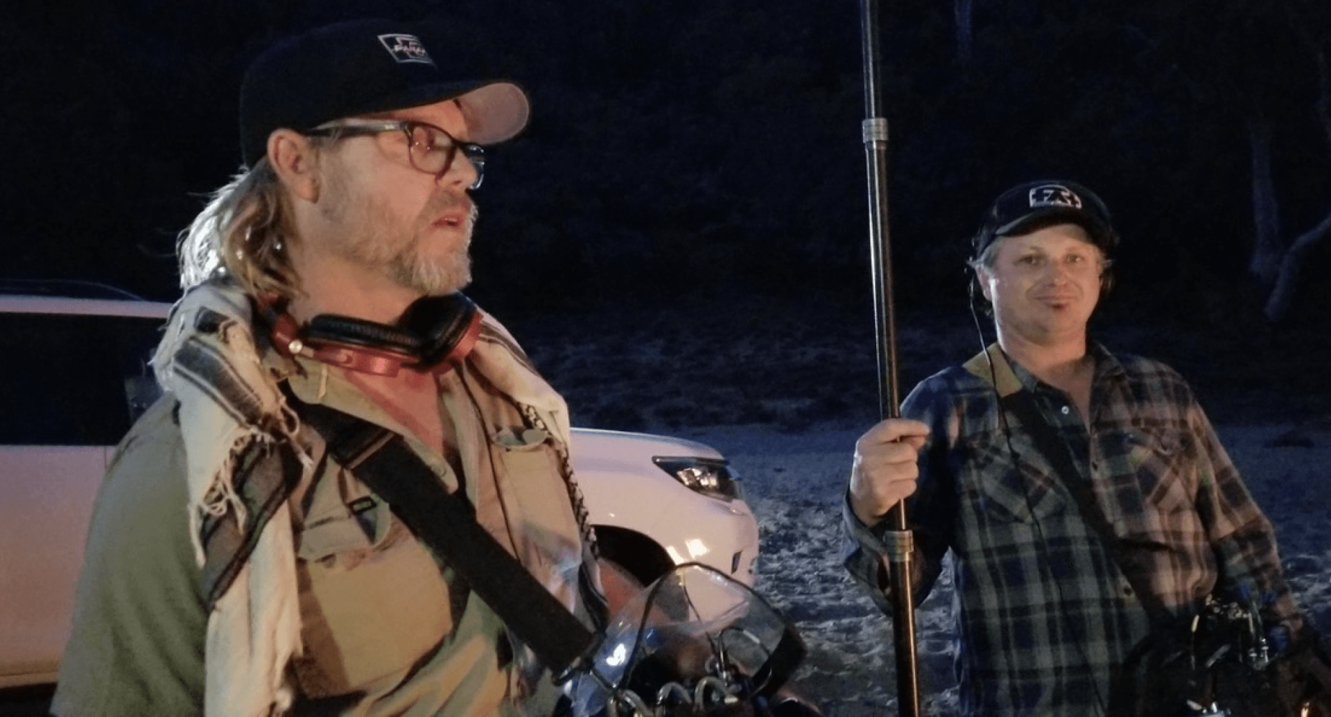 Two men are standing next to each other holding fishing rods.