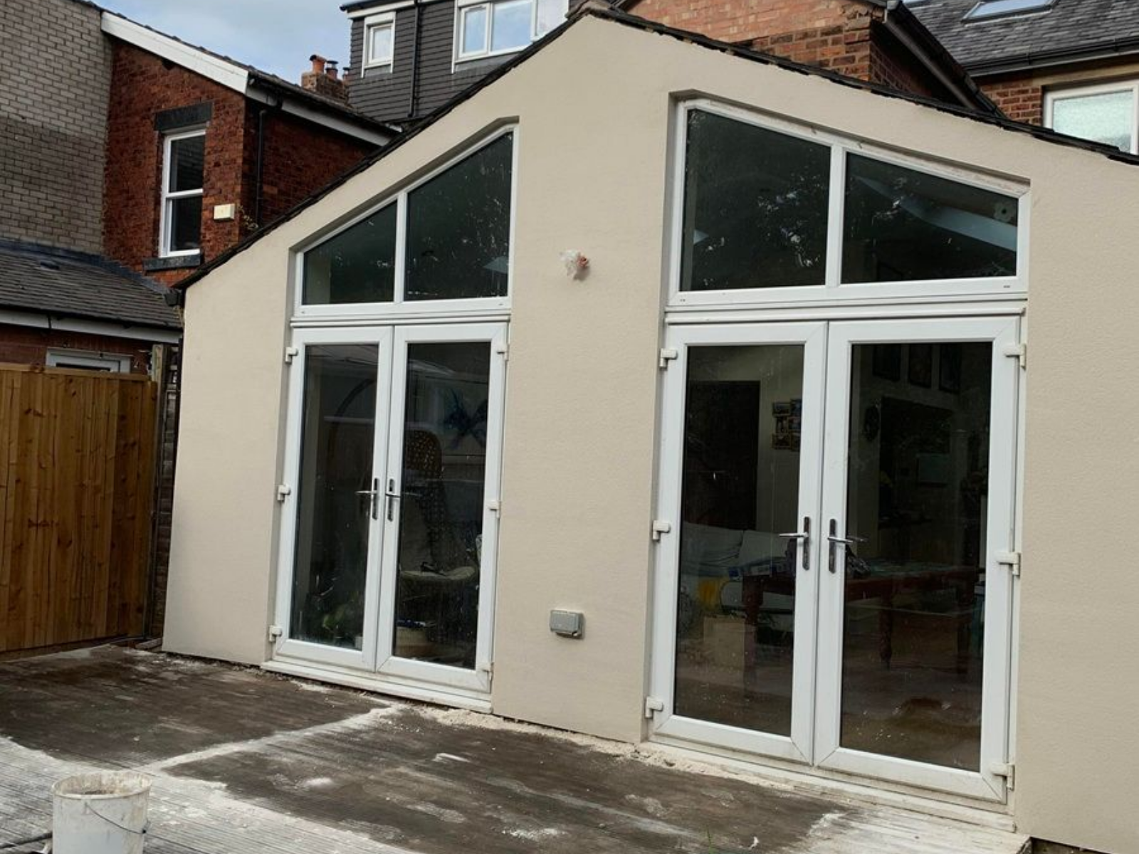 Person applying stucco to a building wall near a window, with scaffolding.