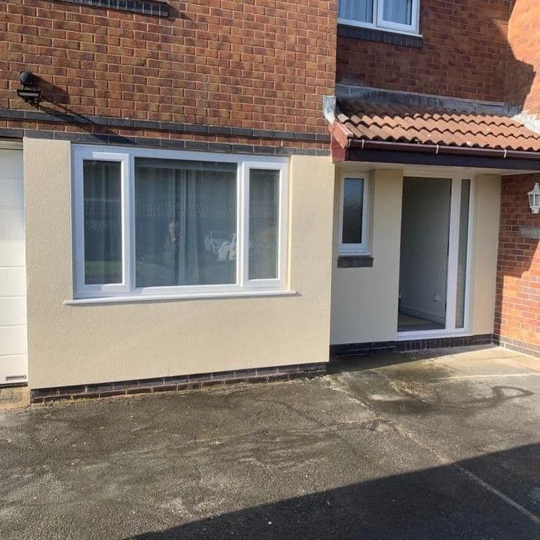Beige stucco facade with white window frames and a red-tiled roof.