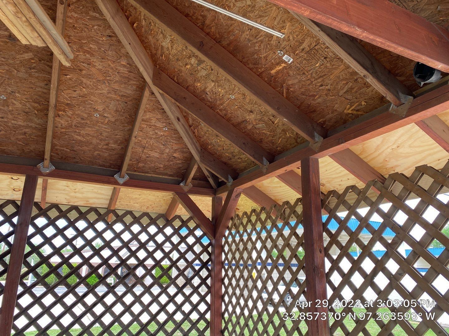 Interior view of a wooden gazebo with latticework and roof structure.