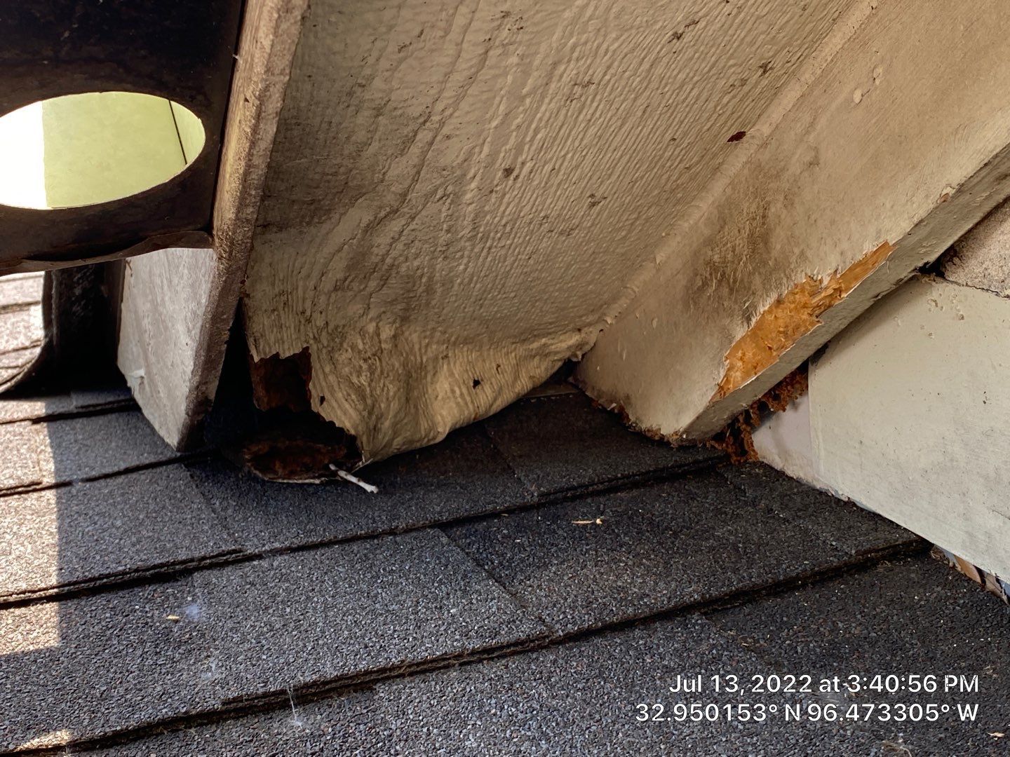 Damaged roof overhang with crumbling edges; dark asphalt shingles in the foreground.