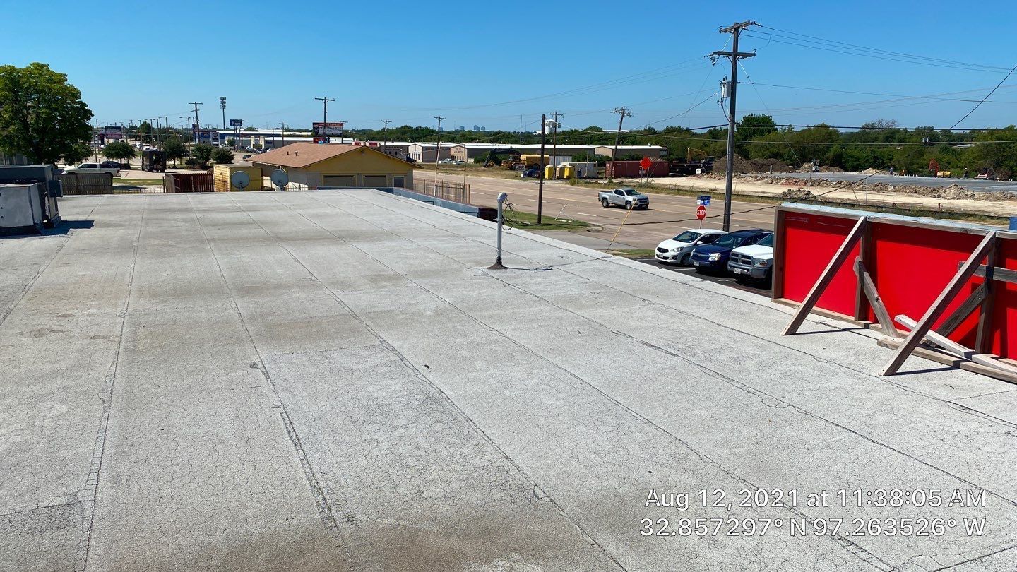 View from a rooftop, showing a parking lot, buildings, and a clear blue sky.