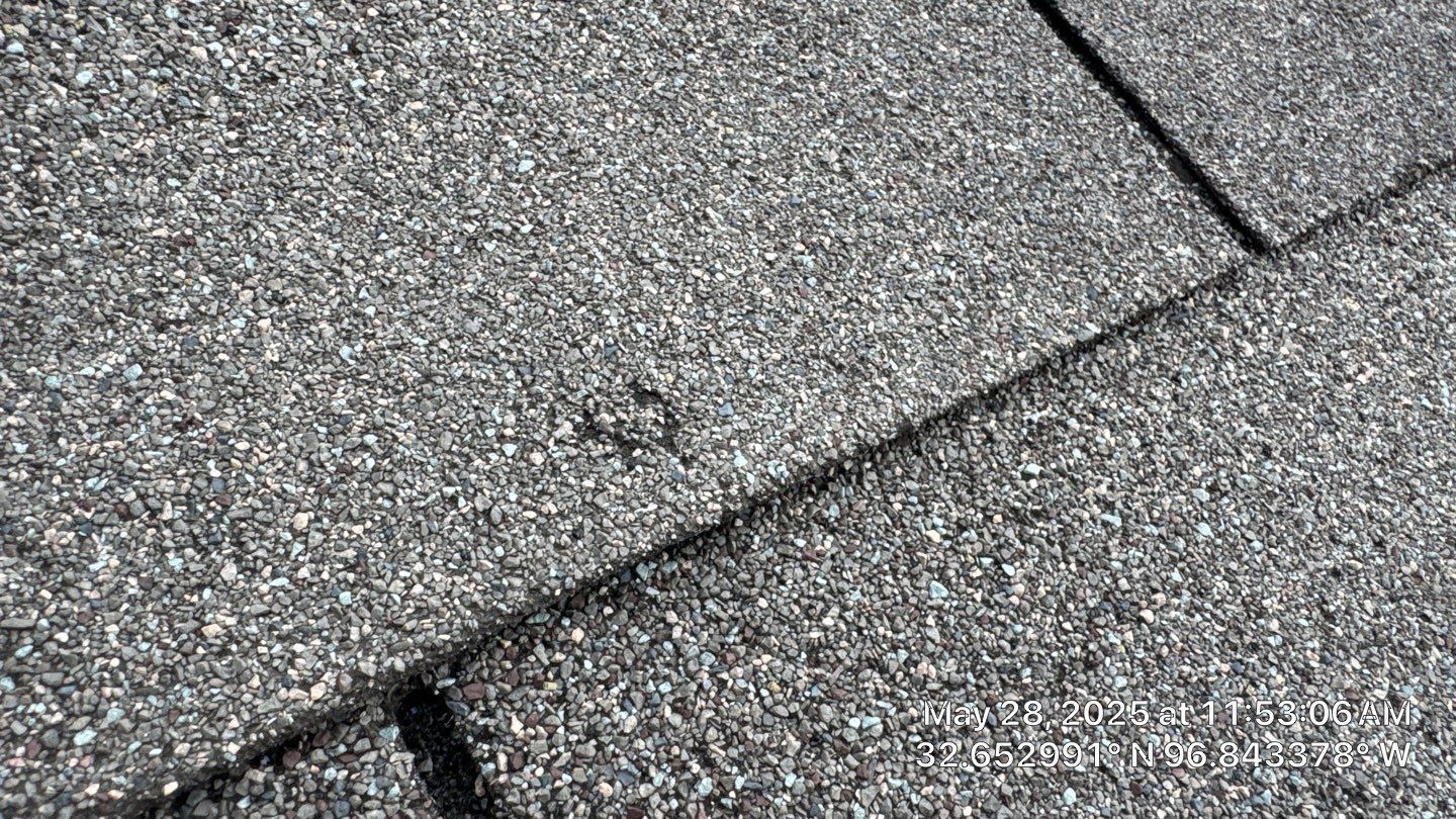 Close-up of gray asphalt roof shingles, showing texture and seams.