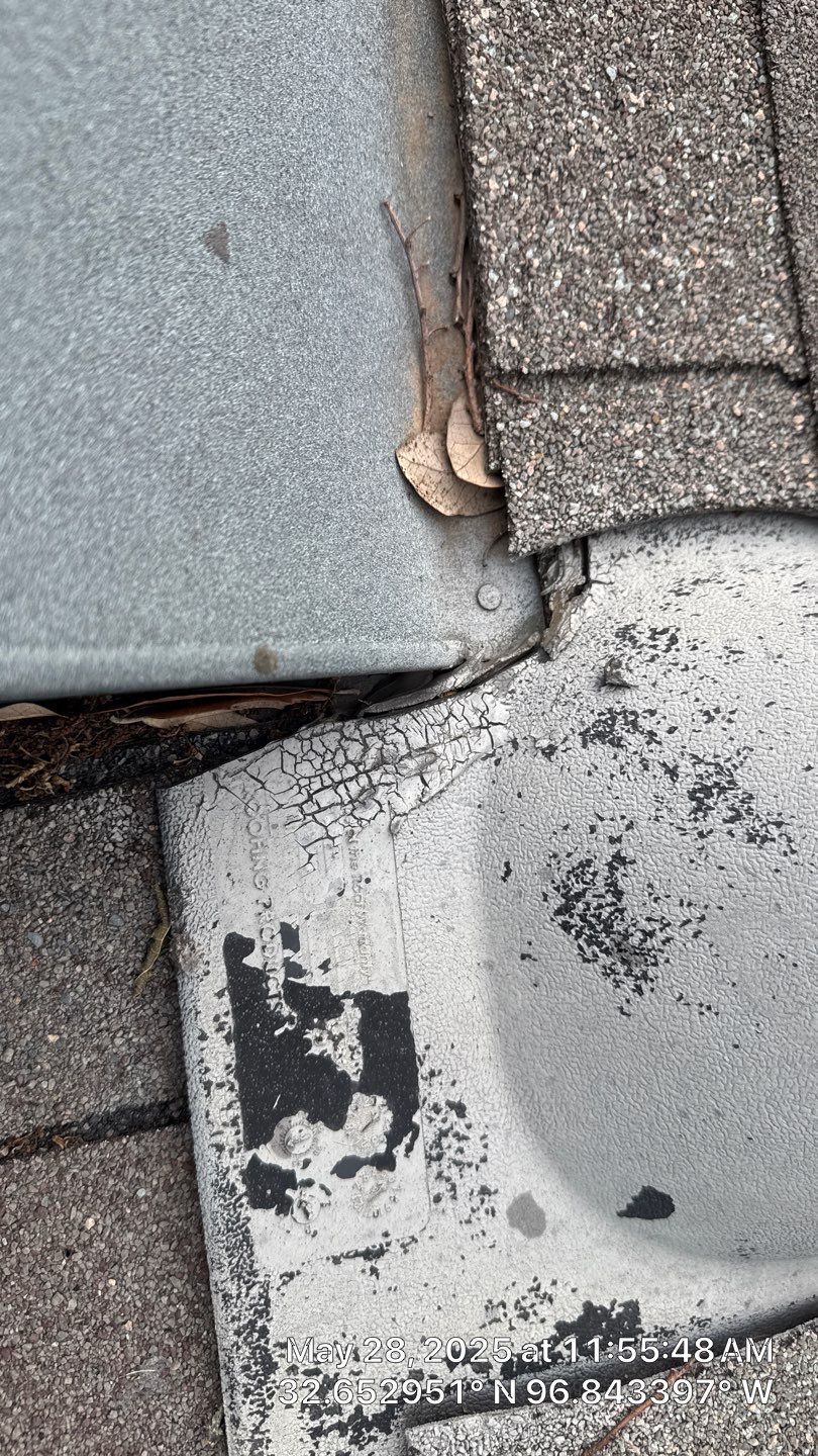 Close-up of weathered gray roof shingles and a metal flashing.