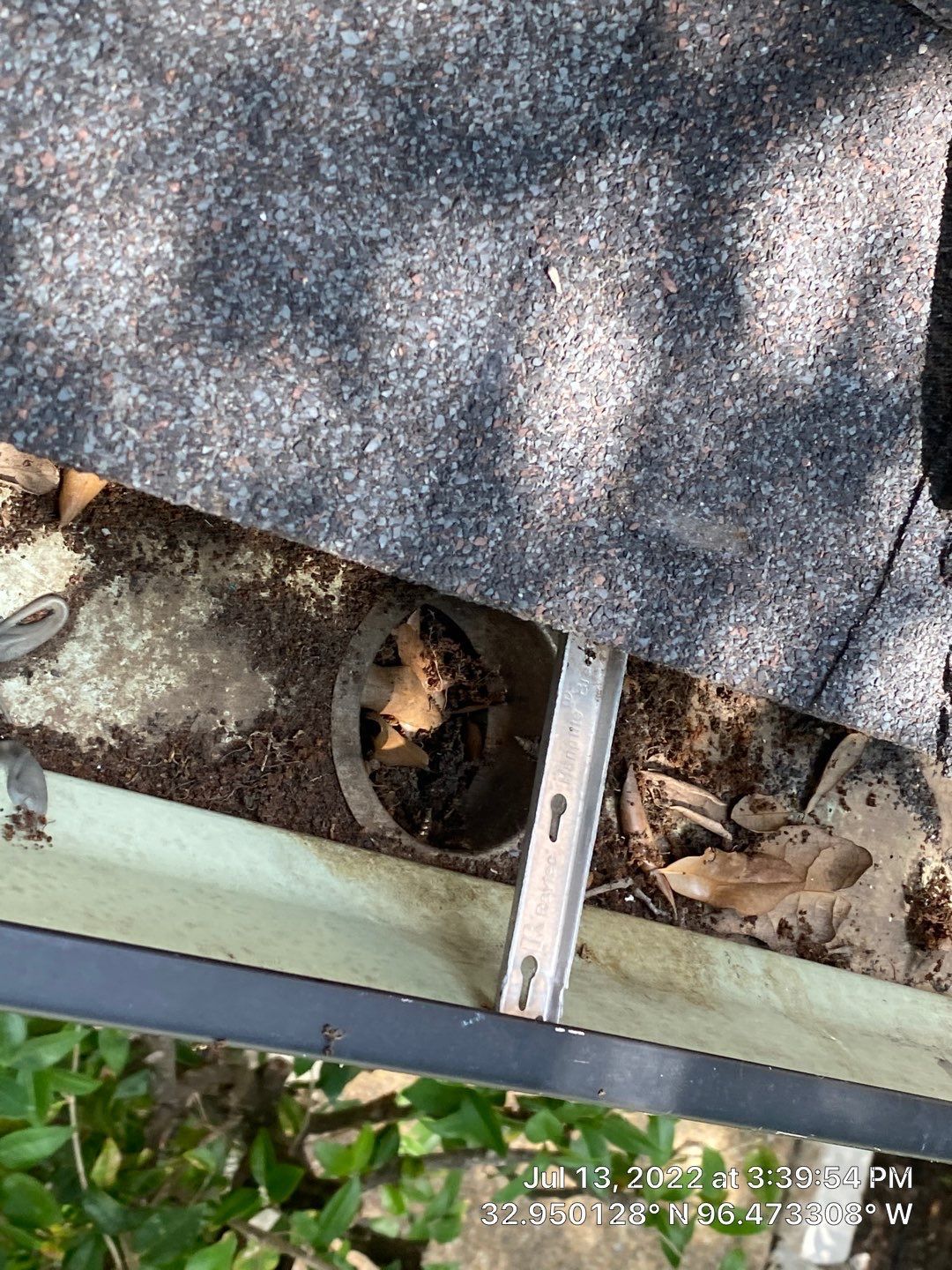 Gutter filled with leaves and debris, partially blocking the downspout.