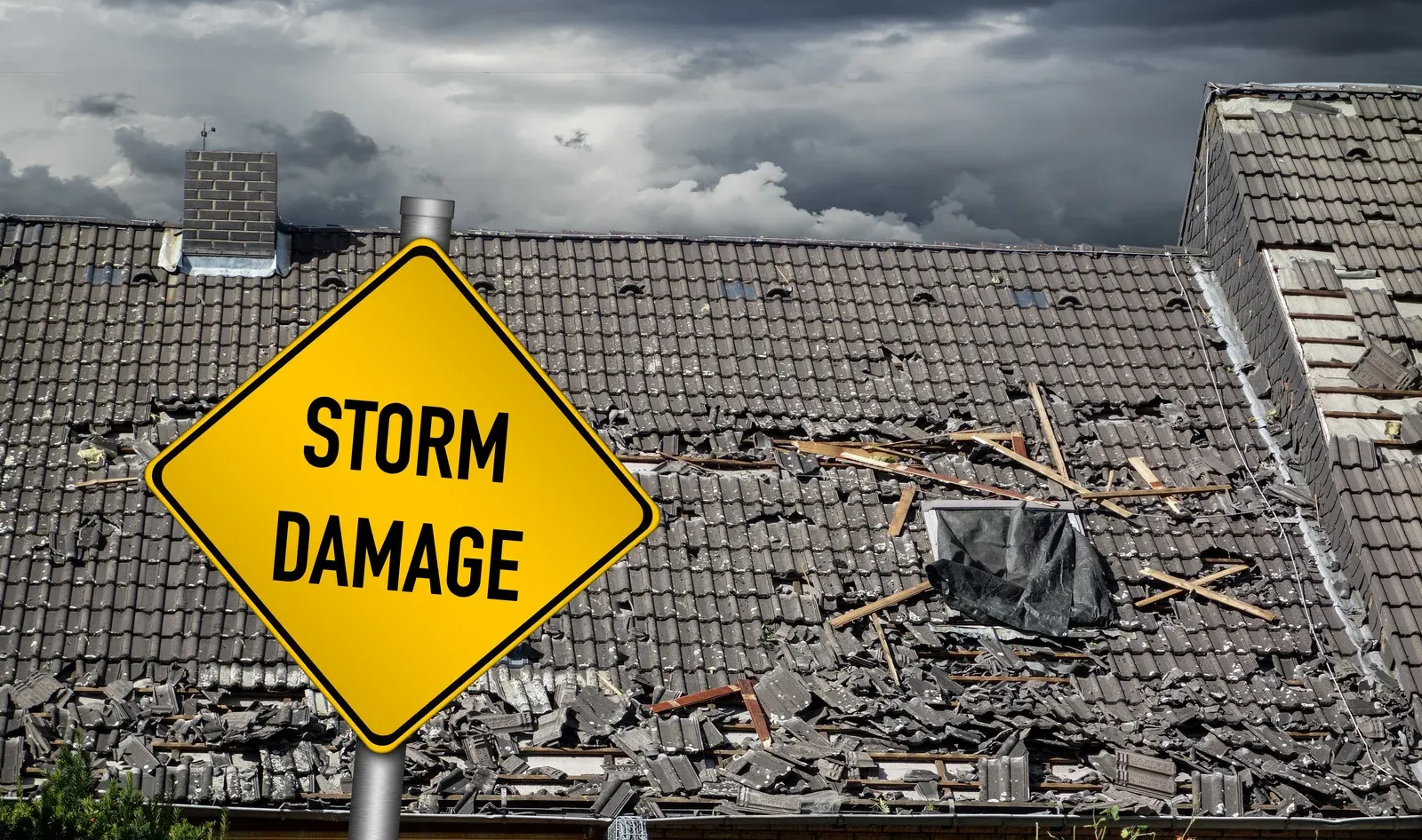 Yellow storm damage warning sign with destroyed roof. Dark, cloudy sky.