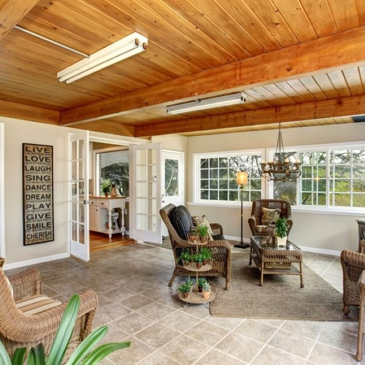 Sunroom with wicker furniture, wood ceiling, tile floor, and large windows.
