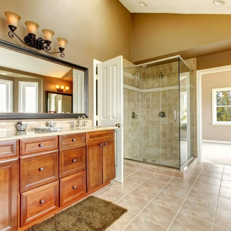 Bathroom with wooden vanity, large mirror, glass shower, and tile floor.